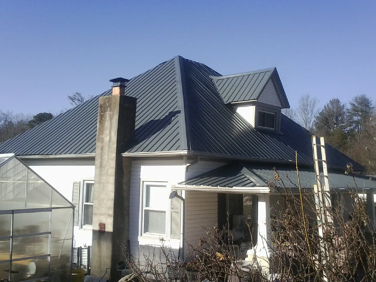 Dark blue standing seam metal roof on a white farmhouse with dormer — Slate & Tile Roof Repair by Roofing Brothers in Amelia