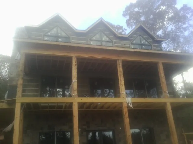 Dormers and porch framing on a large log home under construction — Roof Coating work by our crew in Amelia