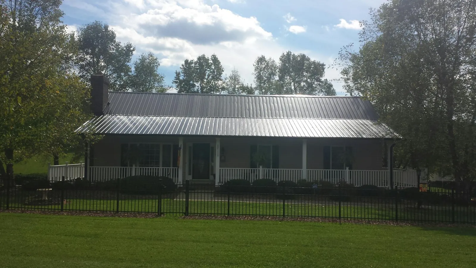 Gray metal roof on a brick ranch with a full width front porch — Gutter Guard Installation work by our crew in Amelia