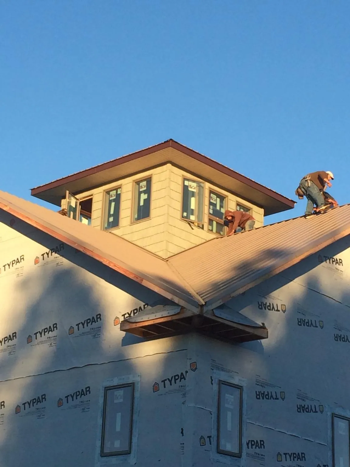 Roofers working around a rooftop cupola on a new metal roof at sunset — Roof Waterproofing in Amelia by Roofing Brothers